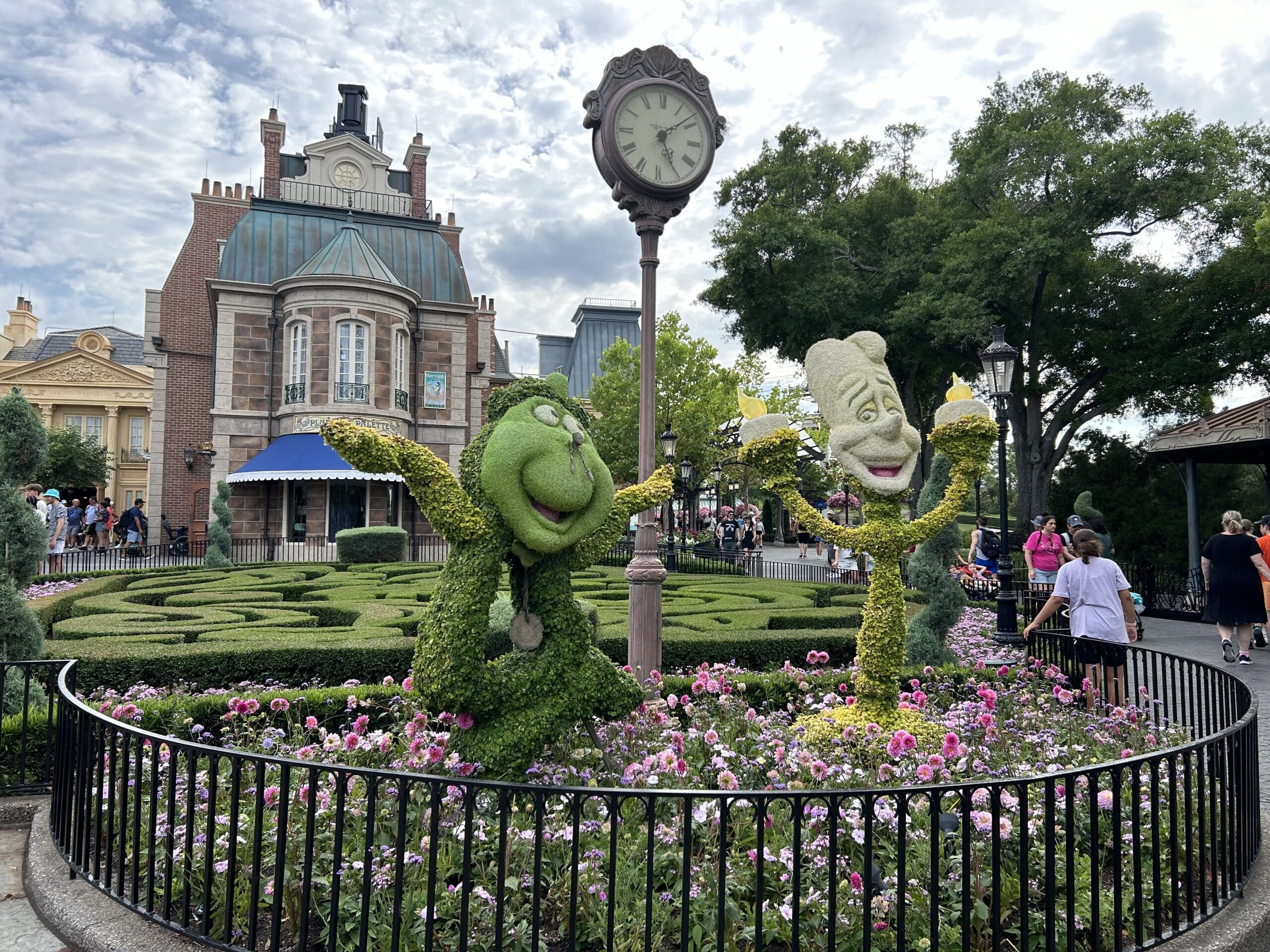 Cogsworth and Lumiere topiary surrounded by flowers at EPCOT Flower and Garden Festival in France pavilion