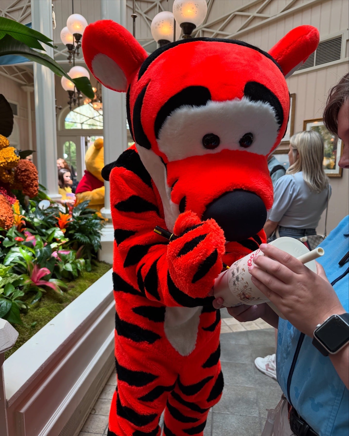 Tigger from Winnie the Pooh signing an autograph for a guest at Crystal Palace character dining in Magic Kingdom.