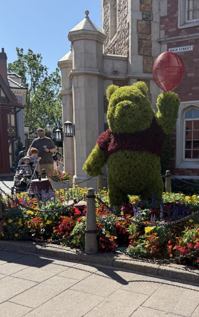 EPCOT Guide: Best Rides, Food & World Showcase Tips 7 Winnie the Pooh topiary holding red balloon at EPCOT Flower and Garden Festival UK pavilion Disney World