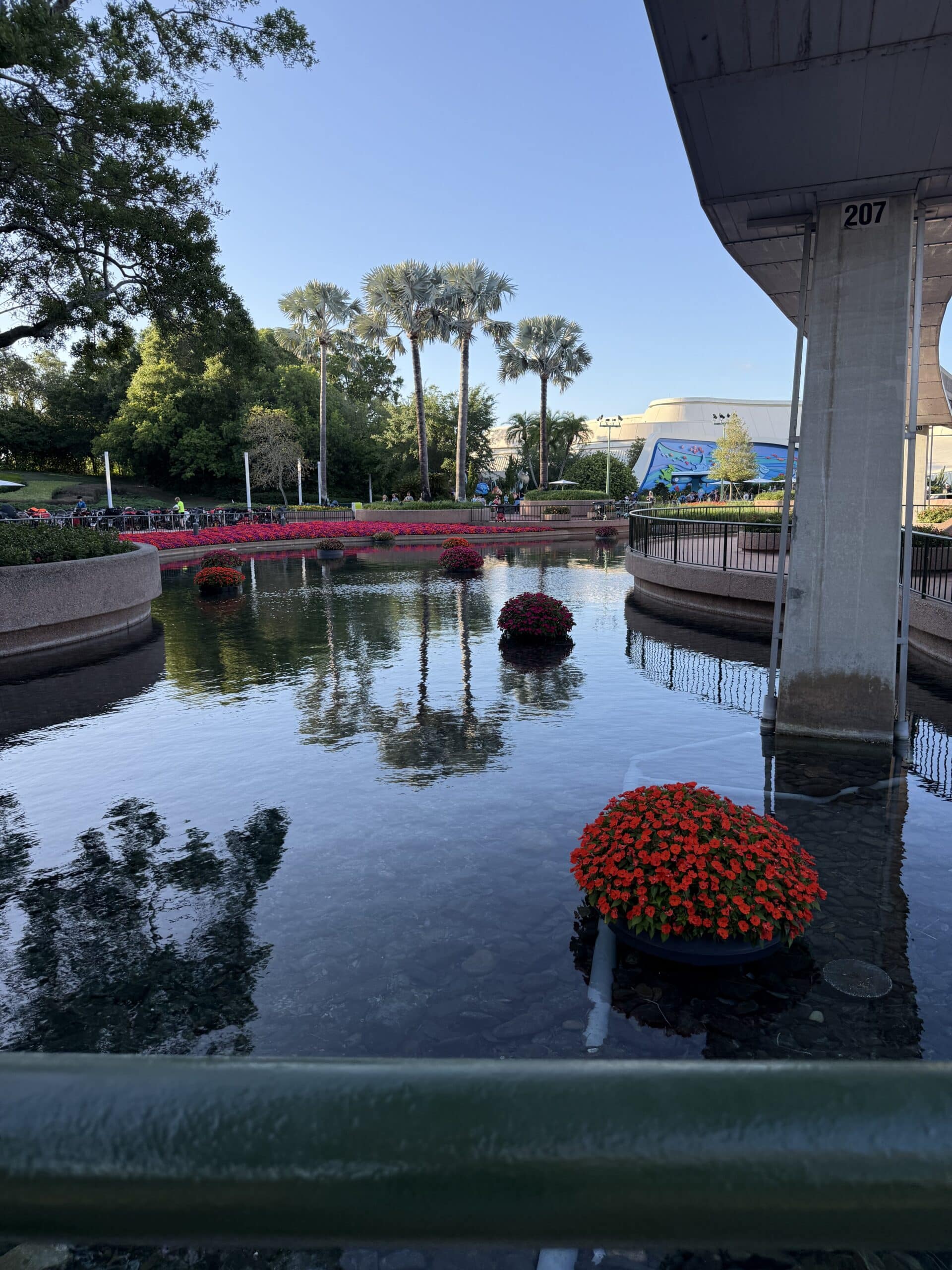 EPCOT Flower & Garden Festival lagoon with floating flower displays, palm trees, and monorail track in Future World at Walt Disney World.