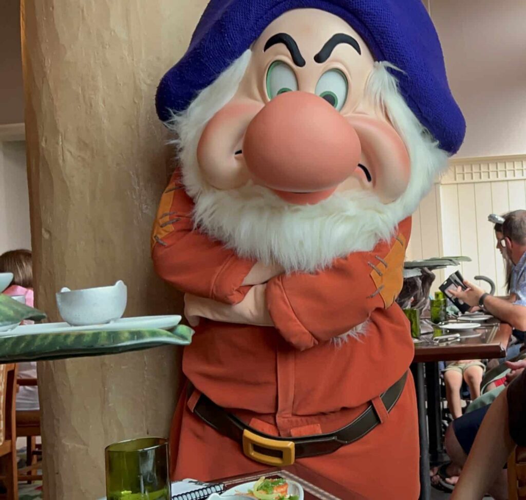 Animal Kingdom Review: Enchanting Extras + Storybook Dining 6 Grumpy posing with guests at Artist Point Snow White character dining